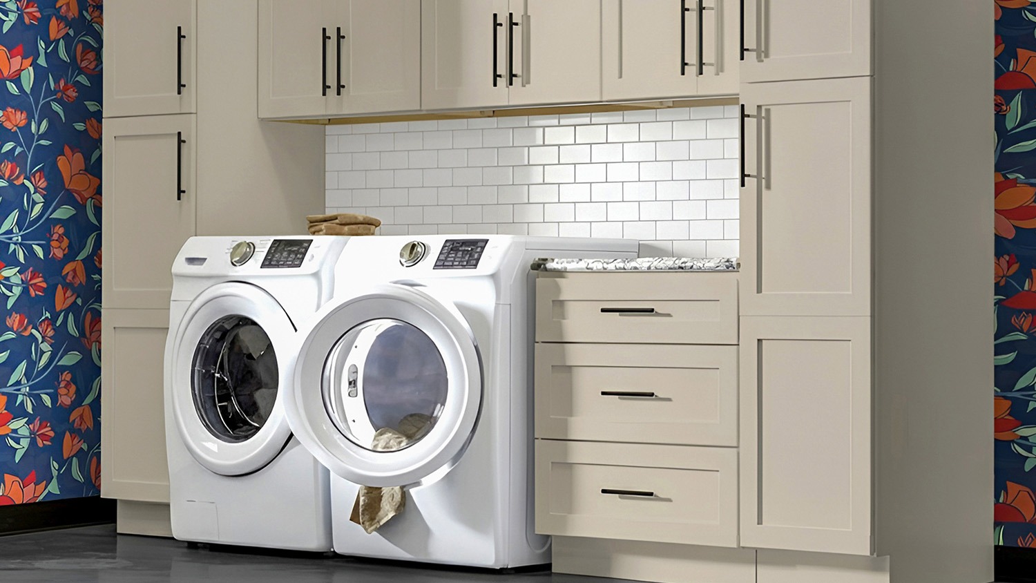 Laundry room with sand-colored cabinets above a front-load washer and dryer